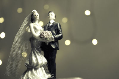 Close-up of wedding cake figurine against defocused illuminated lights