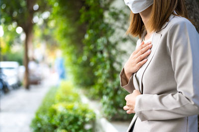 Midsection of woman standing by tree in city