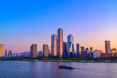 Sea by modern buildings against clear sky