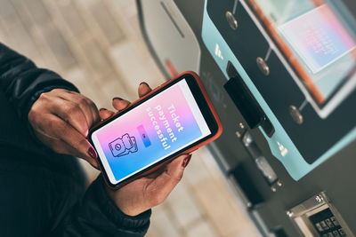 Woman buying ticket at ticket machine paying using mobile payment app on smartphone. female buying