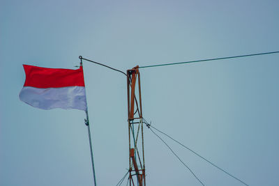 Low angle view of flags against clear blue sky