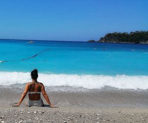 Rear view of woman on beach against clear blue sky