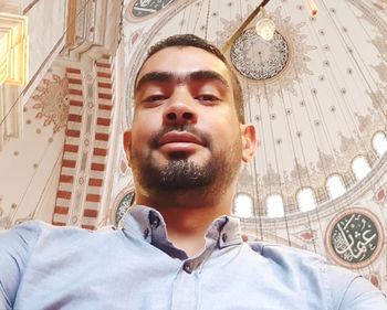 Portrait of young man standing against built structure