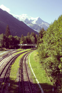 Railroad tracks amidst trees and mountains against sky