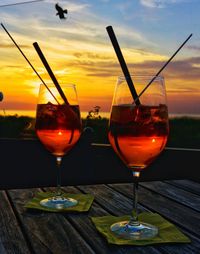 Wine glasses on table against sky during sunset