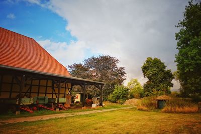 Houses and trees on field against sky