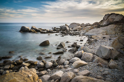 Rocks on beach against sky during sunset