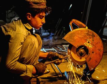 Side view of man cutting metal