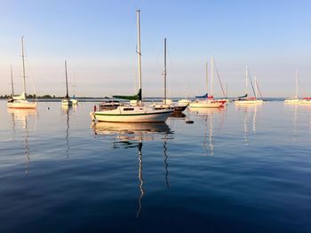 Sailboats moored on sea against sky