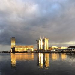 City at waterfront against cloudy sky