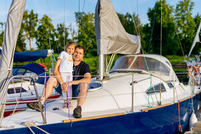 Portrait of girl with father sitting on yacht