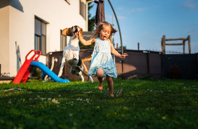 Baby girl running with beagle dog in backyard on summer day. domestic animal with children concept.