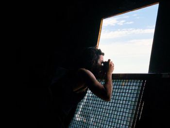 Side view of a woman looking through window