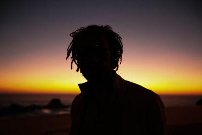 Close-up of silhouette man standing at beach during sunset