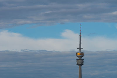 Communications tower in city against sky