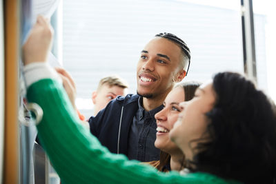 Happy university students checking bulletin board for test results