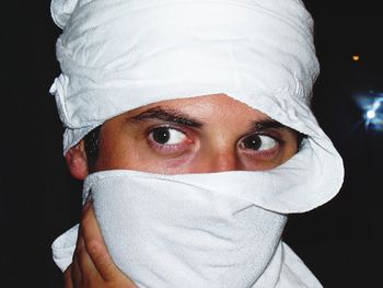 Close-up of man with face covered by bandana at night