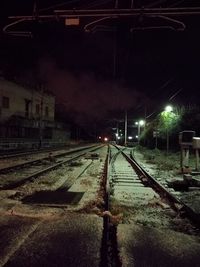 Railroad tracks against sky at night