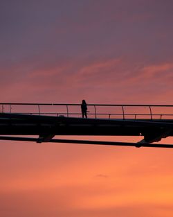 Silhouette man on bridge against sky during sunset
