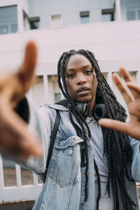 Woman with hair locs gesturing in front of fence