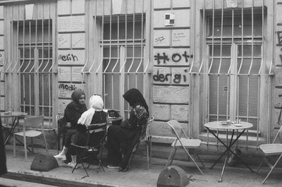 People sitting on chair against buildings