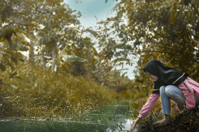 Side view of woman wearing hat against trees