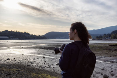 Man photographing at beach against sky