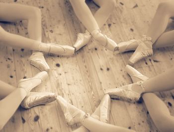 Low section of ballerina sitting on floor in studio