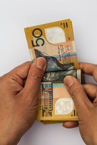 Close-up of human hand holding paper against gray background