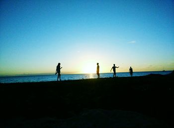 Silhouette of people on beach at sunset