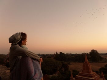 Woman looking at historic temples against sky during sunrise