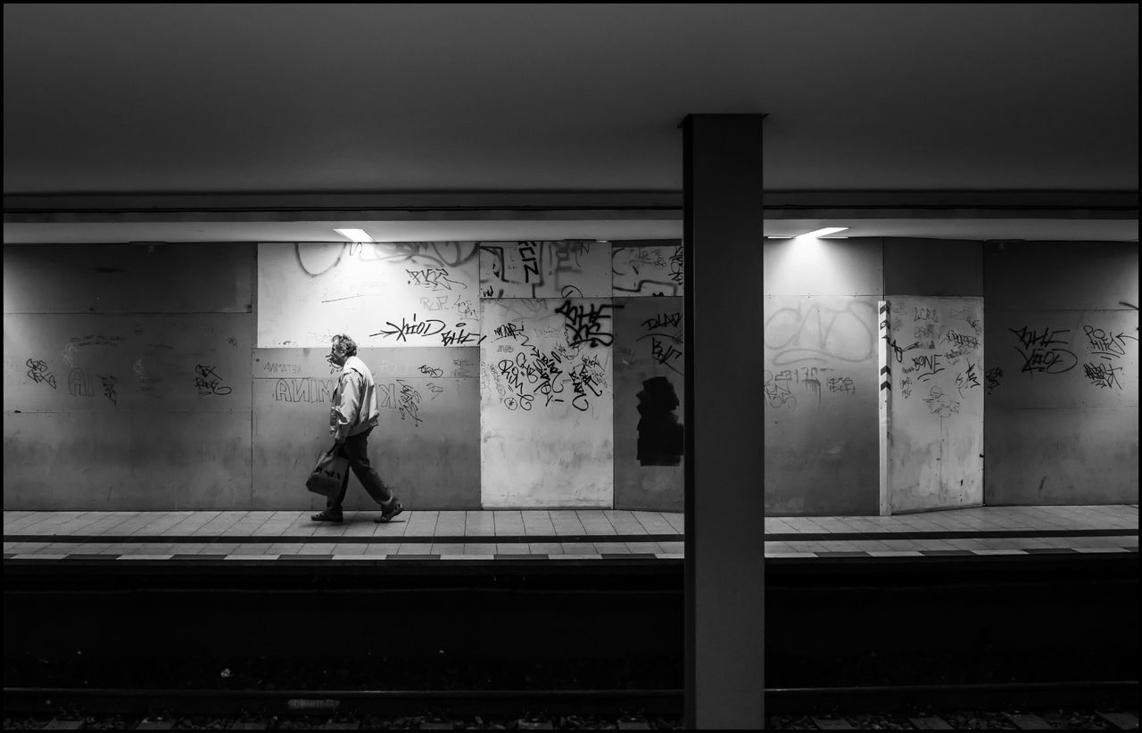 indoors, built structure, architecture, text, full length, art and craft, art, wall - building feature, human representation, creativity, graffiti, men, lifestyles, door, illuminated, wall, western script