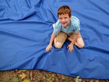 Portrait of boy sitting on blue sheet