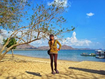 Full length of woman standing on beach against sky
