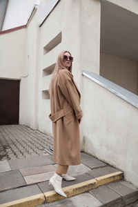 Female fashion model, posing for a full length photo, wearing total beige outfit, street fashion