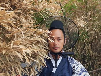 Portrait of man in traditional clothing standing against plants