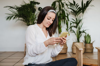 Midsection of woman using mobile phone while sitting outdoors