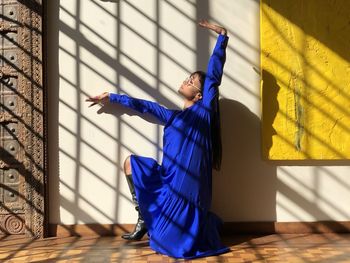 Midsection of person standing against blue wall