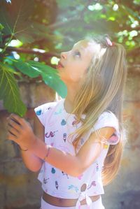 Girl looking away while standing against tree