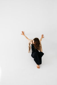 Side view of woman exercising against white background