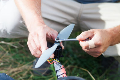 Midsection of man repairing machinery on field