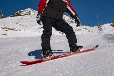 Low section of man snowboarding on snow covered mountain