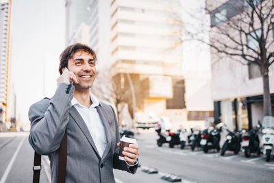 Businessman talking on phone while standing on road