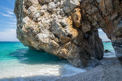 Rock formation on sea shore against sky