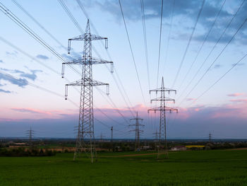 Low angle view of electricity pylon on field against sky