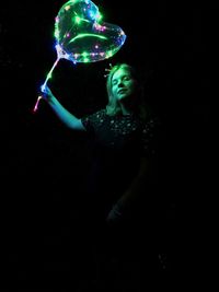 Portrait of woman holding bubbles over black background