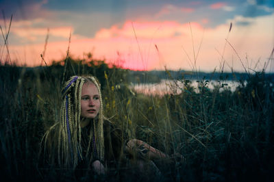 Young woman on field against sky during sunset