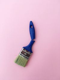 Directly above shot of broken paintbrush on pink background