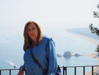 Portrait of mature woman standing against sea