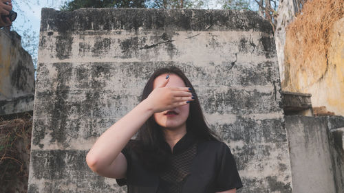 Portrait of teenage girl standing against stone wall